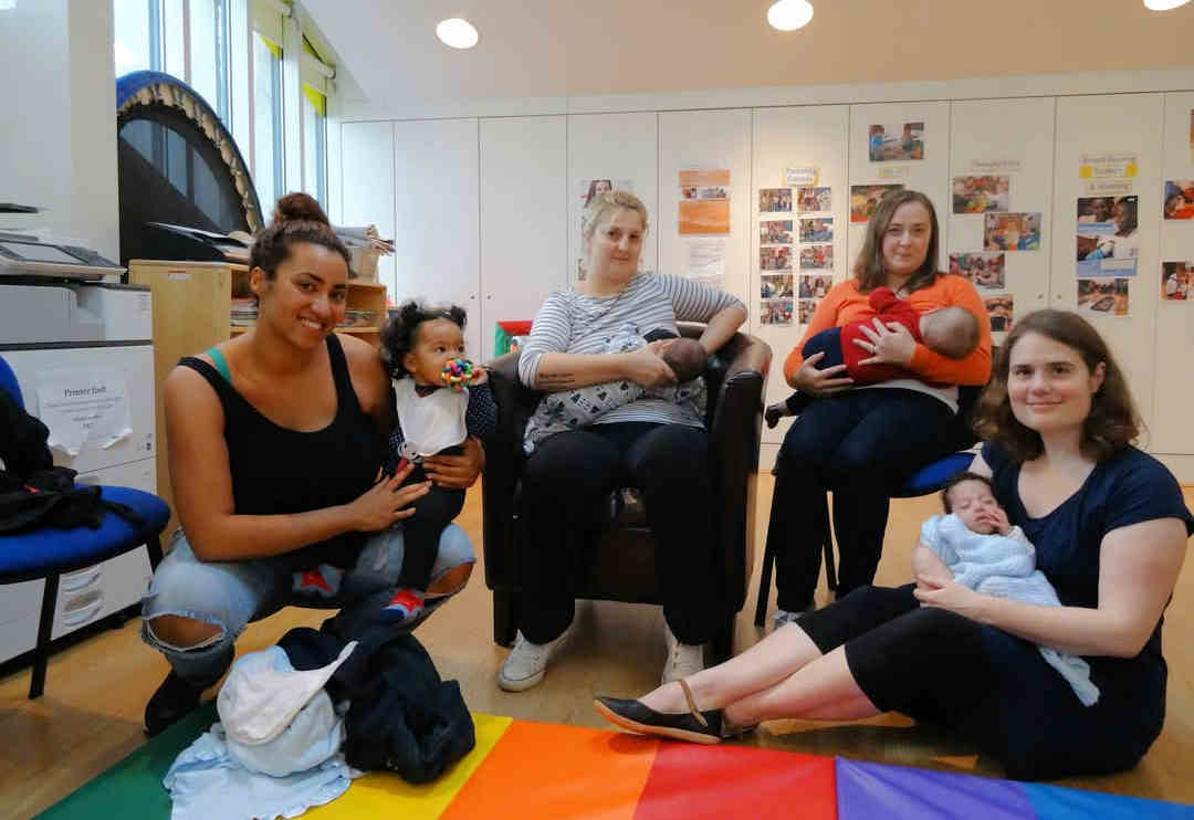 Midwife with mother breastfeeding baby